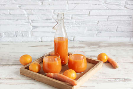 Fresh carrot and tangerine juice . Healthy vitamins drink in a glass on wooden table background.の写真素材