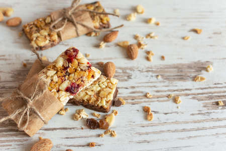 Cereal granola bar with nuts, fruit and berries on wooden table background. Healthy sweet homemade dessert snack.の写真素材