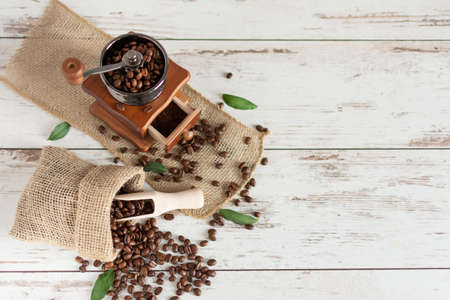 Manual vintage coffee grinder and coffee beans in a burlap bag on a wooden table. Copy space.の写真素材