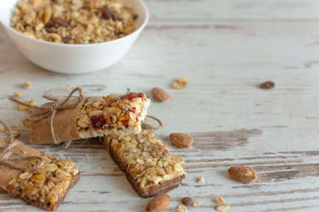 Cereal granola bar with nuts, fruit and berries on wooden table background. Healthy sweet homemade dessert snack.の写真素材