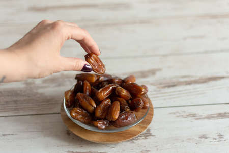Bowl of dried dates on wooden background with space for text. Ramadan food concept.の写真素材