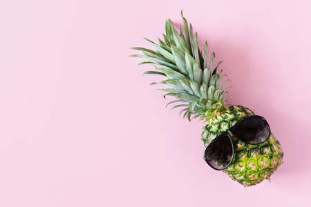 Funny pineapple with sunglasses on pink pastel background top view. Summer background. Summer vacations.の写真素材