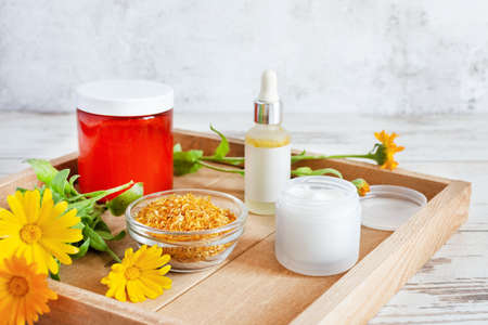 Herbal cosmetics with calendula flowers. Natural organic moisturizer cleansing product. Homemade calendula natural cream and oil.の写真素材