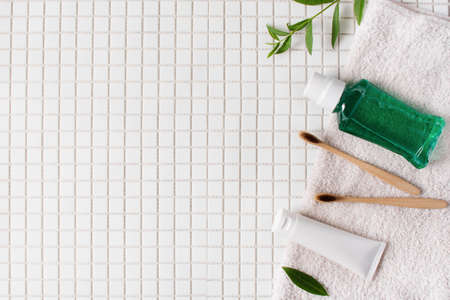 Bamboo toothbrush, toothpaste and rinse for teeth on white mosaic background top view. Dental hygiene concept. Sustainable lifestyle.の写真素材