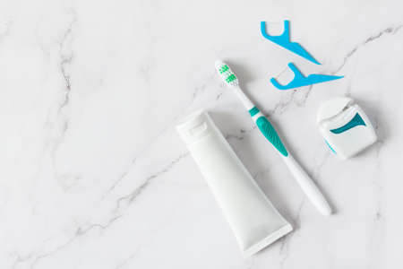 Toothbrush, toothpaste and dental floss top view on white marble background. Dental hygiene concept.の写真素材