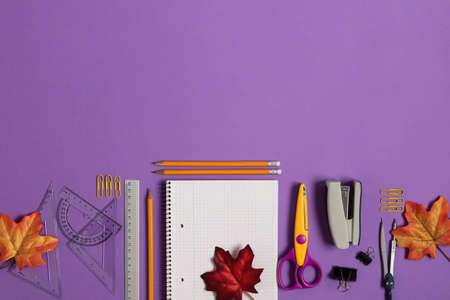 Blank notebook with school and office supplies on purple background top view. Back to school concept. Copy space.の写真素材
