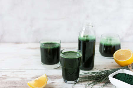 Spirulina drink with lemon and spirulina algae powder on white wooden table. Superfood, detox drink.の写真素材