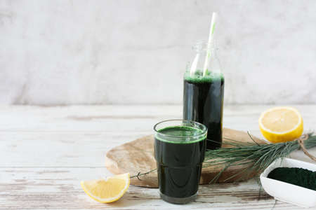 Spirulina drink with lemon and spirulina algae powder on white wooden table. Superfood, detox drink.の写真素材