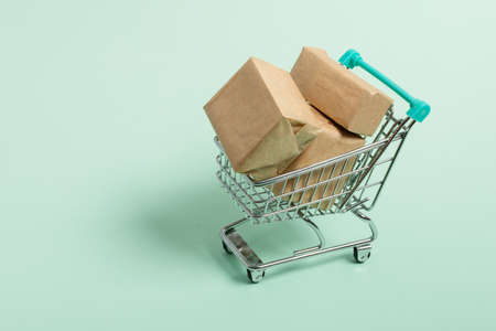 Shopping cart with package boxes on green background. Shopping and delivering concept.の写真素材