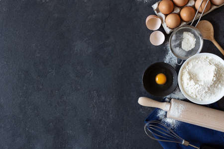Ingredients and tools for dough preparation on black background top view. Baking background.