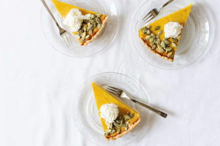 Slices of fresh homemade pumpkin pie on white table top view. Traditional American pumpkin pie.