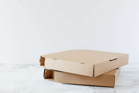Cardboard pizza boxes on table over white background with copy space. Pizza delivery service.