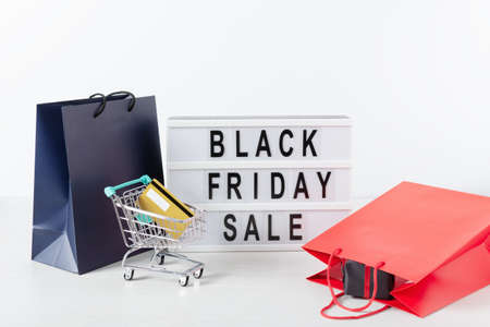 Lightbox with black Friday text, shopping cart with credit cart and shopping bags over white...