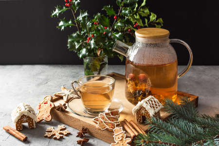 Glass teapot with blossoming tea and tea cup on grey table with Christmas gingerbread cookies. Christmas holiday tea ceremony.の写真素材