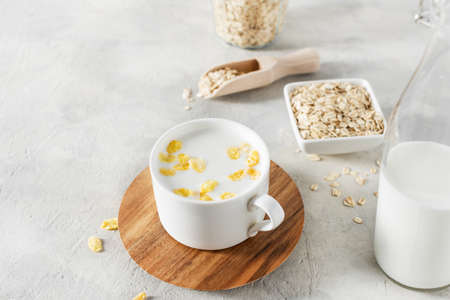 A cup of homemade non dairy alternative milk made from oat flakes. Vegan oat milk on grey concrete table.の写真素材