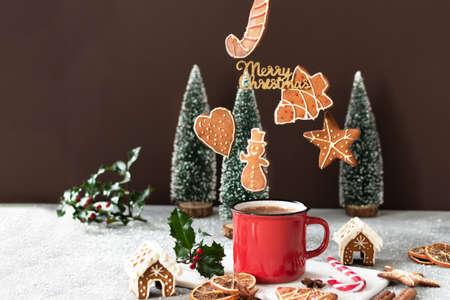 Christmas cappuccino and gingerbread cookies levitating above red mug on grey concrete table with...