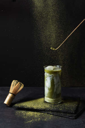 Japanese iced matcha latte and matcha tools on black background. Refreshment ice matcha tea with milk.の写真素材