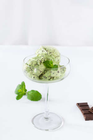 Scoops of mint ice cream with chocolate crumbs in a glass over white background. Summer refreshing...