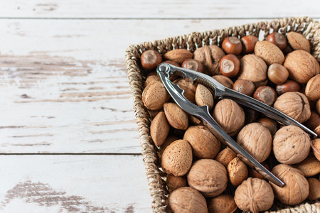 Variety of shelled nuts and nutcracker on wooden background. Superfood for healthy eating.