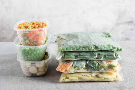 Plastic containers and bags with different frozen vegetables. Preserved vegetables. Healthy eating.の写真素材