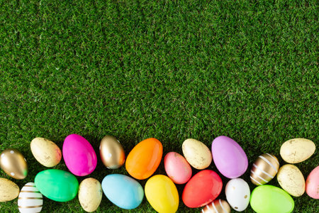 Colorful Easter eggs on grass background top view. Easter holiday greeting card.