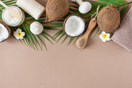 Natural coconut oil for body care and massage with beauty tools top view on brown collar background....