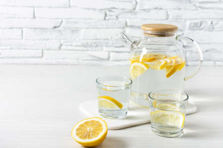Lemon detox water in the morning on wooden background.
