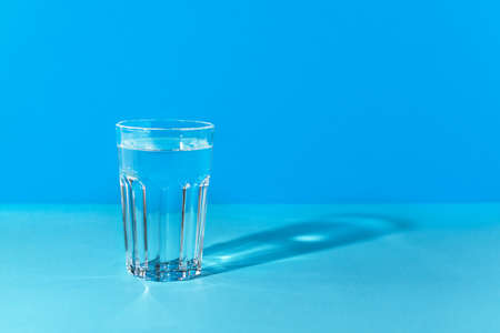 A glass with water in a blue colors background. Refreshment drinking water, dieting and health care beverage.の写真素材