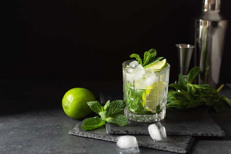 Refreshing summer mojito cocktail with ice cubes, fresh mint and lime on black. Exotic mojito beverage.の写真素材