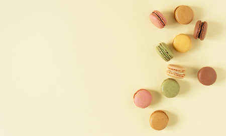 Multi colored french macaroons top view on yellow pastel background. French meringue cookie macarons.の写真素材