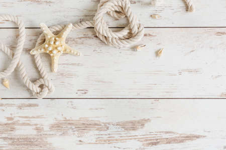 Sea background with marine rope and seashells on white wooden deck top view. Summertime sea background.の写真素材