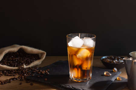 Iced coffee in a glass on black background. Cold refreshment summer coffee drink.
