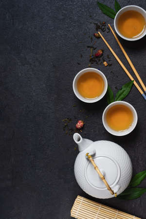 Teapot and tea cups with tea drink top view on black background. Asian tea ceremony.の写真素材