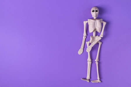 Halloween background with human skeleton on purple background top view. Halloween greeting card.の写真素材