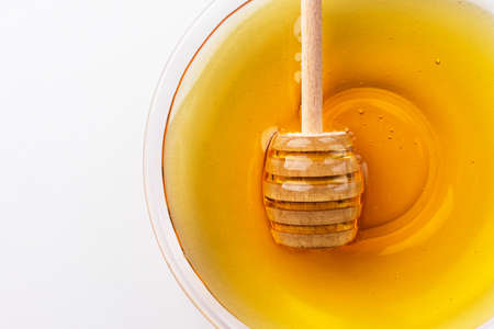 Healthy organic honey in a plate with wooden honey dipper top view on white background. Sweet honey healthy dessert.の写真素材