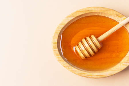 Healthy organic honey in a bowl with wooden honey dipper top view. Sweet honey healthy dessert.の写真素材