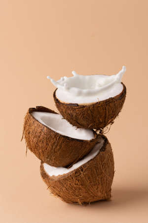Halved coconut with milk splash. Creative composition with coconuts and milk.の写真素材
