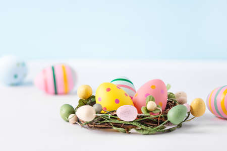 Multi coloured easter eggs in nest on white background. Happy Easter greeting card. Easter...