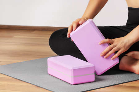 Woman yoga workout with yoga blocks on yoga mat indoor. Healthy lifestyle.の写真素材
