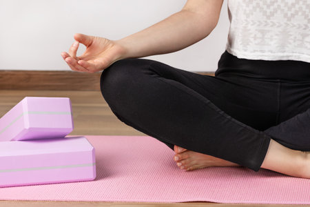 Yoga woman sitting in lotus asana and breathing. Yoga workout with yoga blocks.の写真素材