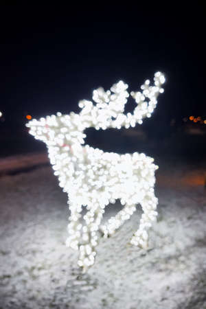 Christmas deer in a defocused lights outdoor. Christmas illumination.の写真素材