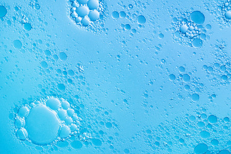 Oil and water bubbles on blue background. Abstract face cleanser bubbles background.
