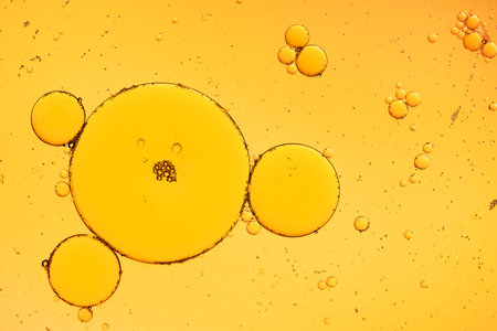 Golden yellow abstract oil bubbles or face serum background. Oil and water bubbles macro photography.の写真素材