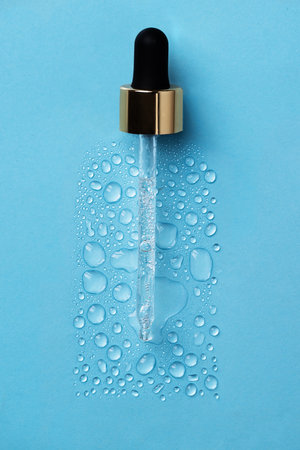 Drops of face serum top view. Liquid gel moisturizer. Creative idea of face serum with pipette on blue background.の写真素材