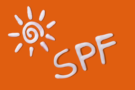 SPF cream. Sunscreen cream in a sun shape on orange background. Creative idea of suntan lotion cream. Sun ultraviolet protection concept.の写真素材