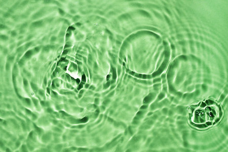 Light green water surface texture with splashes and bubbles. Abstract background for natural beauty products. Green water splashes wallpaper.の写真素材