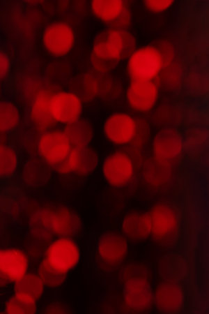 Defocused red holiday bokeh background. Red lens flare Christmas and New Year lights.の写真素材