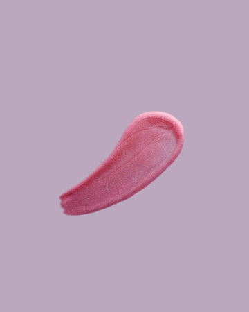 Pink shimmering lip gloss swatch texture on purple background. Lipstick smudged cosmetic product.の写真素材