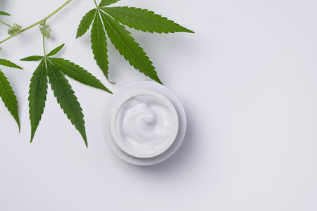 Container of hemp cream top view on white background. Cannabis body cream or face cream with marijuana leaf.の写真素材