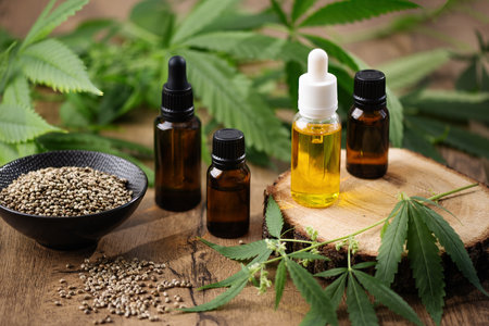 CBD hemp oil in a bottles and hemp seeds with cannabis leaf on wooden background. Hemp herbal alternative medicine.の写真素材